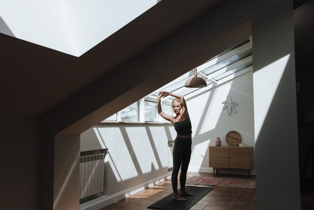 Older woman stretching in a sunlit room